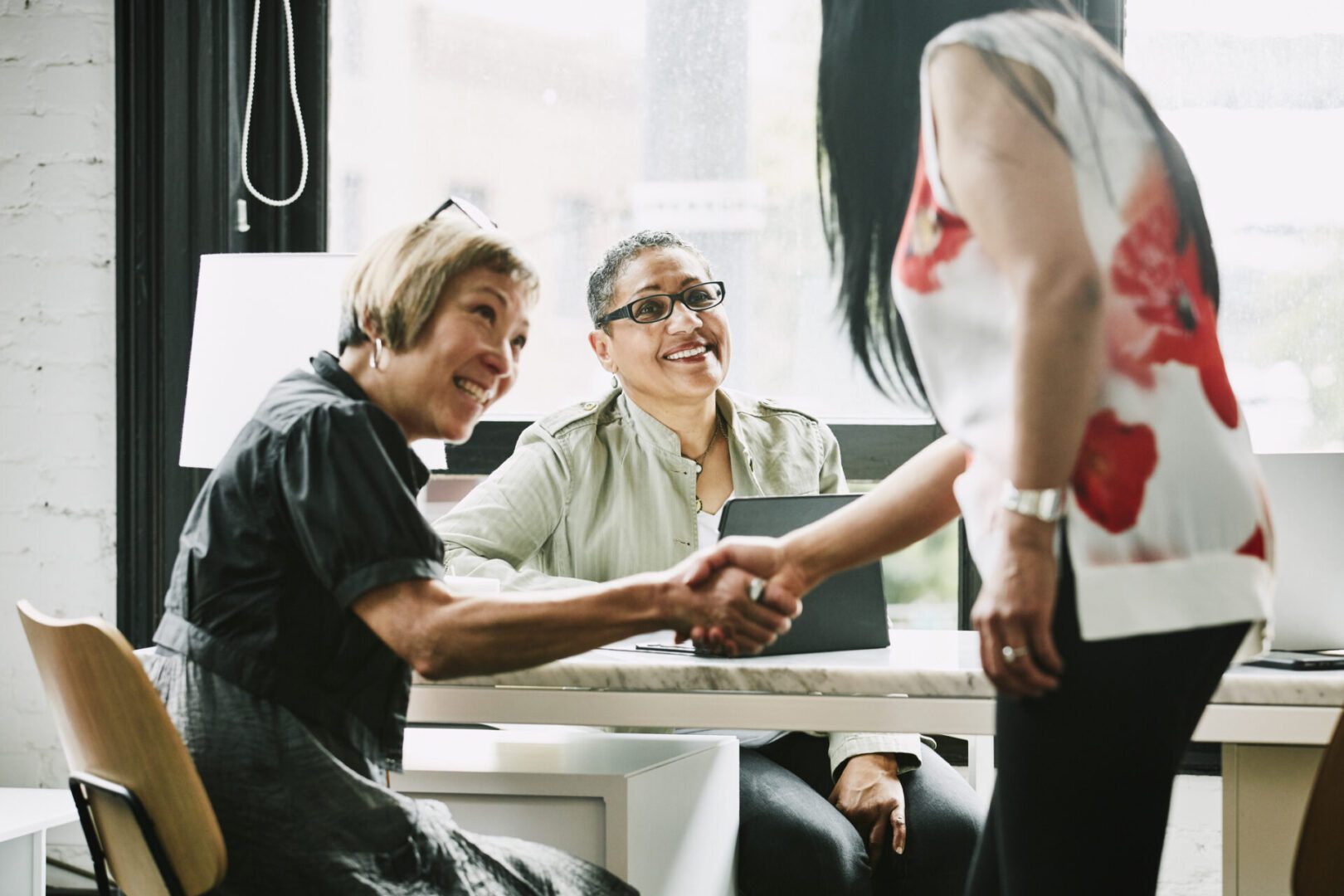 A group of people sitting around a table shaking hands.